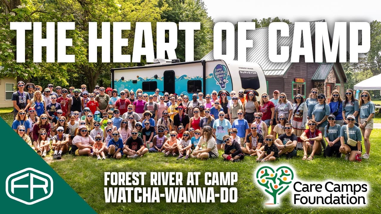 Campers, counselors and the Forest River team posing in front of the camper at Camp Watcha-Wanna-Do